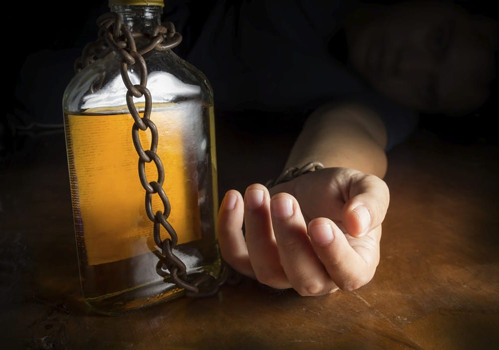 man chained to whiskey bottle